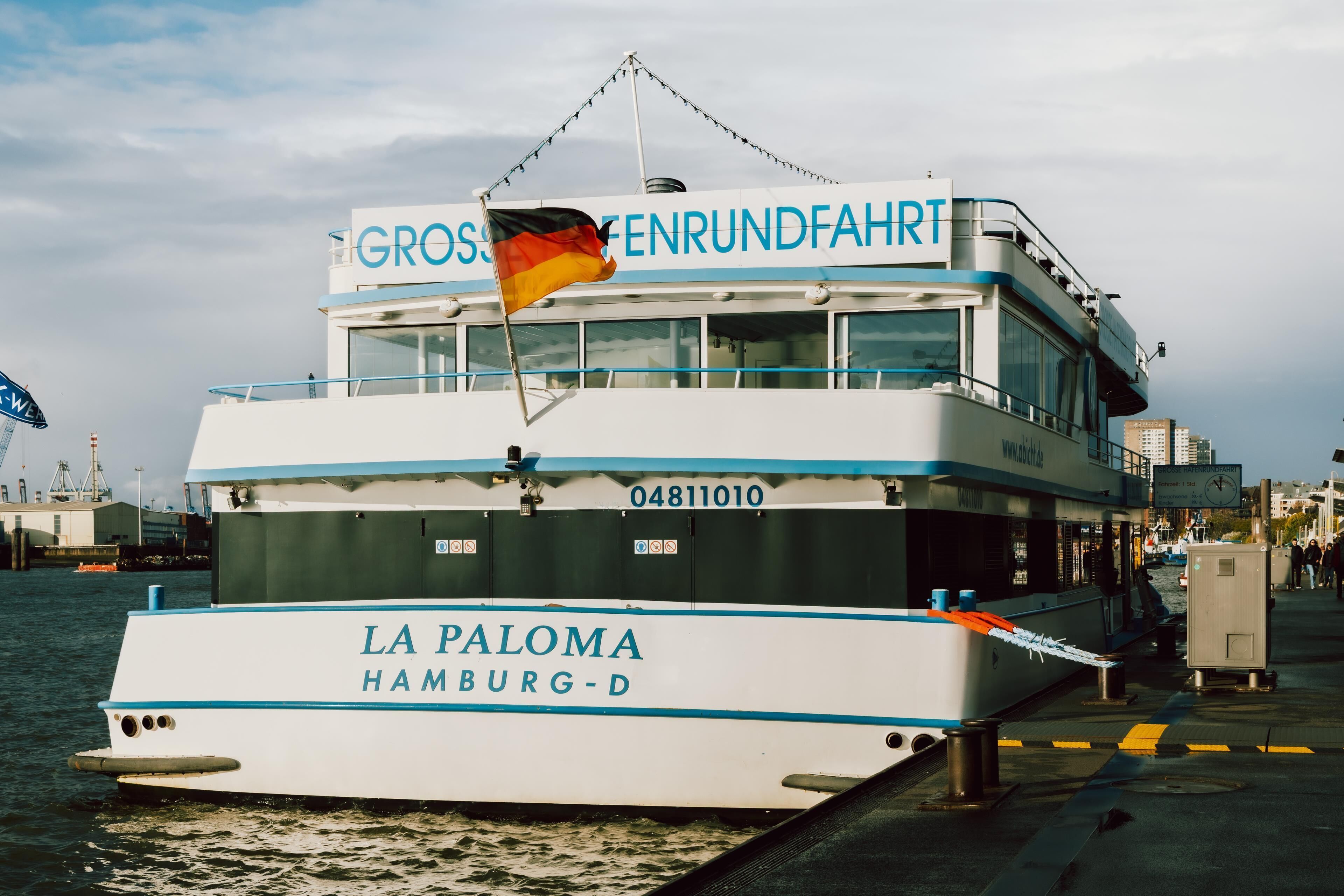 A boat named 'LA PALOMA Hamburg-D' with 'GROSSENRUNDFAHRT' written on the upper deck.