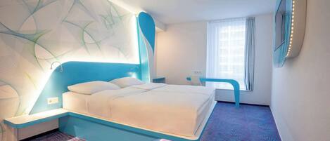A modern hotel room with a large bed, a desk, and a chair.