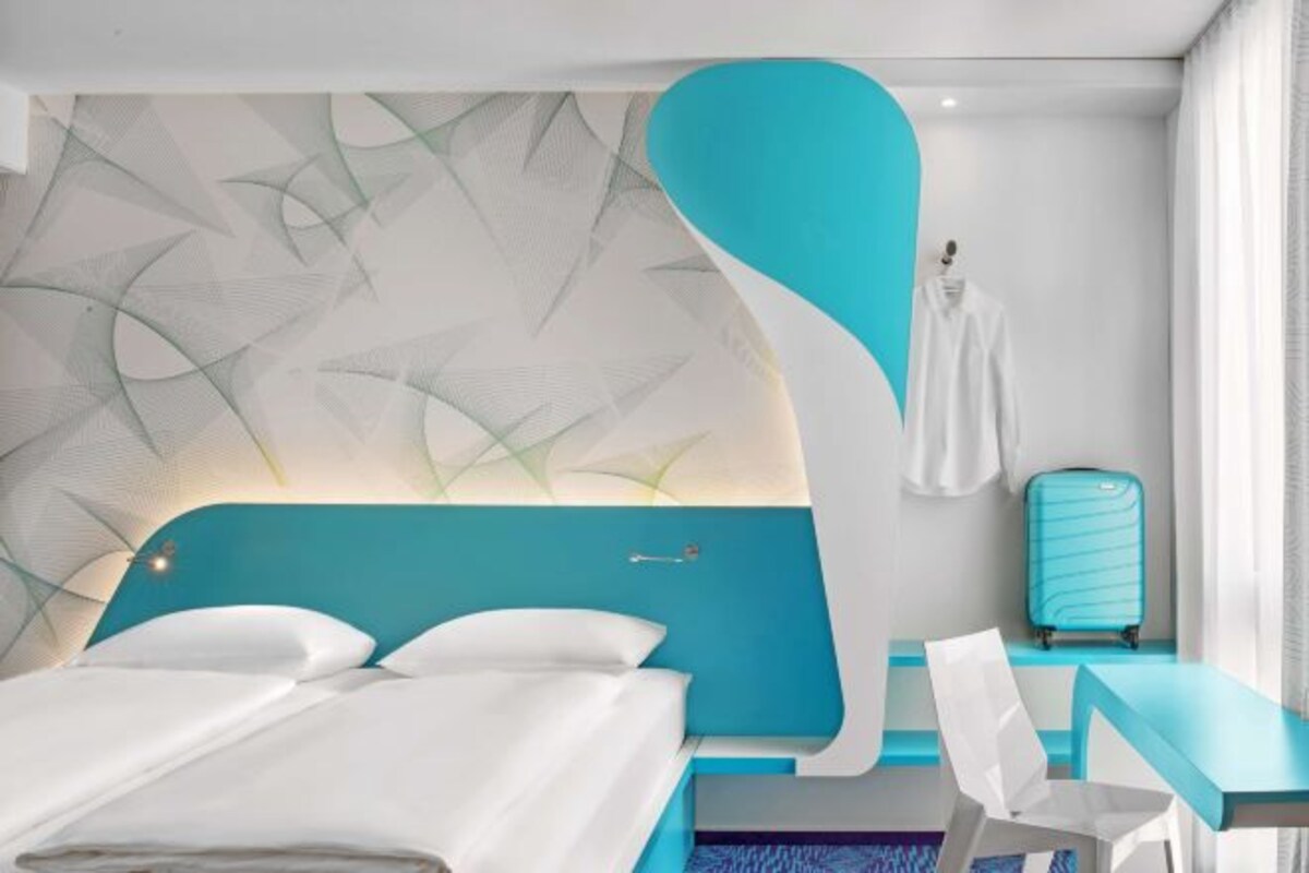 Een moderne hotelkamer met een bed, een bureau en een koffer.