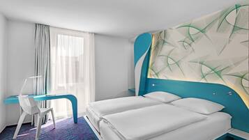 Una habitación de hotel con una cama, un escritorio y una silla.