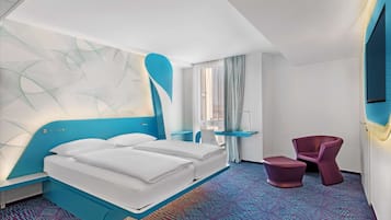 A modern hotel room with a large bed, a desk, a chair, and a large abstract wall art piece.