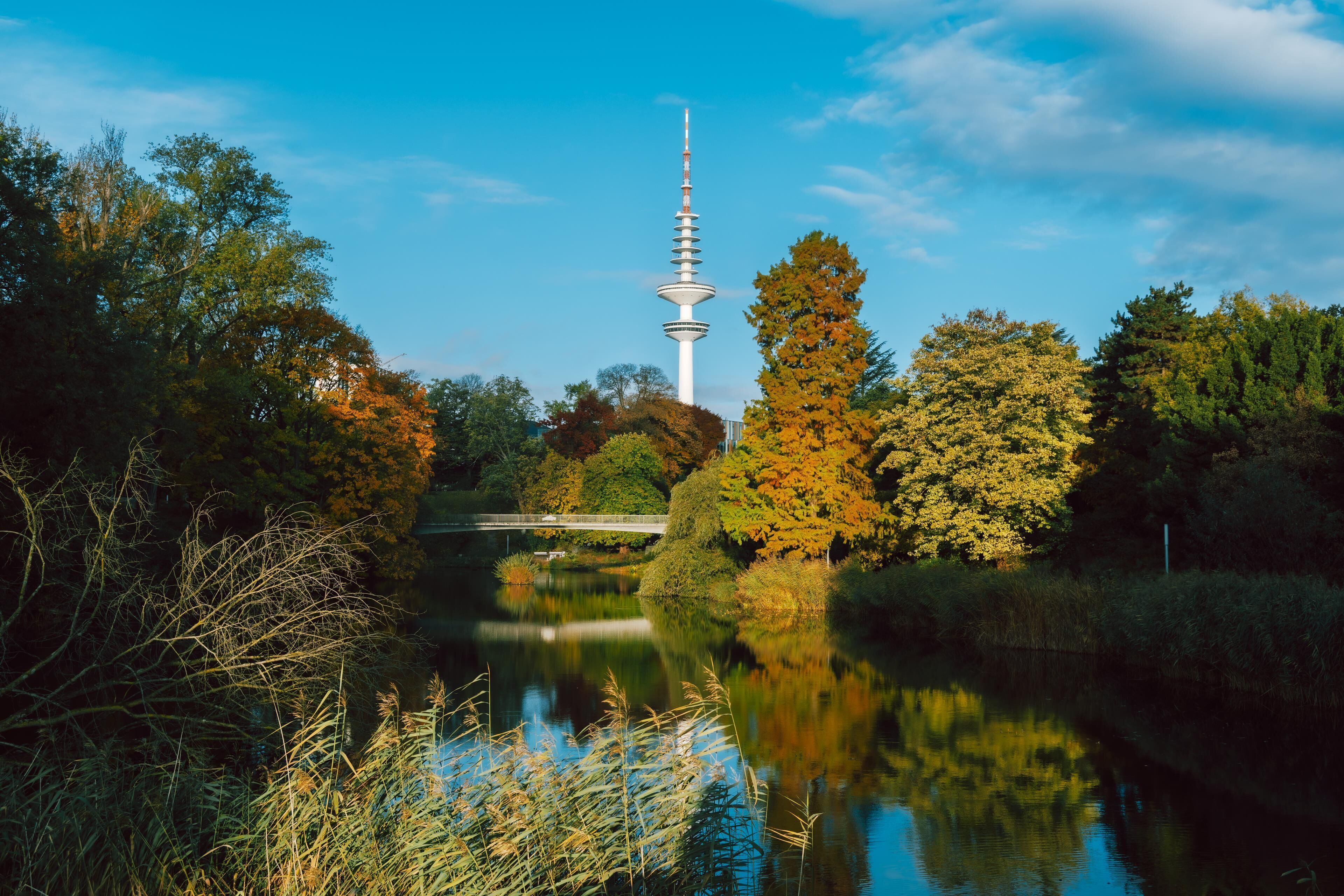 A tower with a spiral design surrounded by trees and a body of water.