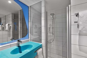 Une salle de bain moderne avec un lavabo bleu, une douche en verre et un grand miroir.