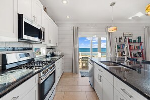 Enjoy a serene dining and cooking experience with a stunning ocean view from this kitchen, featuring a large island with a sink and a stainless steel range.