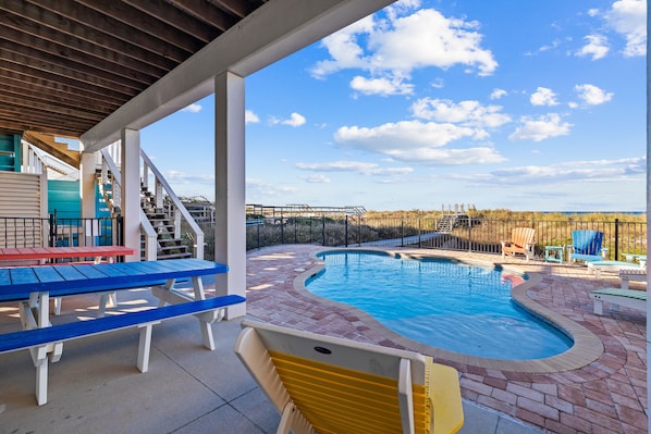Relax by the pool surrounded by a patio with lounge chairs and a table.