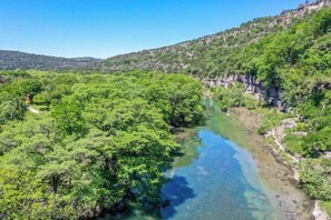Une rivière bordée d’une forêt dense et verdoyante et de falaises rocheuses.