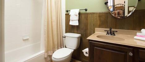 A bathroom with a bathtub, toilet, sink, and a mirror.