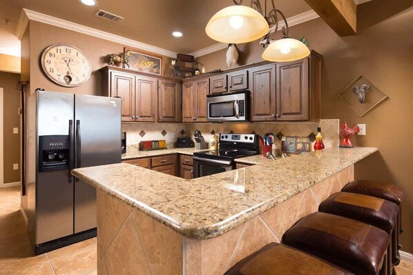 A kitchen with granite countertops, stainless steel appliances, and wooden cabinets.