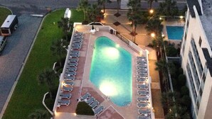 An aerial view of a hotel with a swimming pool surrounded by lounge chairs, a parking area, and a view of the beach. - COUPLES ROMANTIC GETAWAY, OCEANFRONT, HIGH-END DECOR, ADJUST. KING, FREE PARKING (Myrtle Beach)