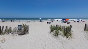 A sandy beach with a wooden fence and some vegetation in the foreground. - COUPLES ROMANTIC GETAWAY, OCEANFRONT, HIGH-END DECOR, ADJUST. KING, FREE PARKING (Myrtle Beach)