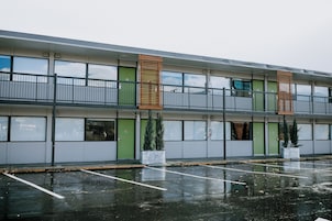 Un immeuble à plusieurs étages, doté d’un toit plat, de grandes fenêtres et d’un parking avec des places délimitées.