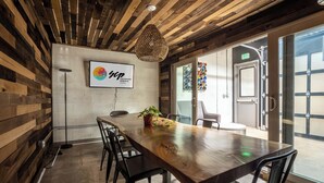 A conference room with a wooden table, black chairs, a hanging light fixture, and a sign for the Colorado Springs Hotel. - SCP WildFree Colorado Springs, Trademark by Wyndham (Colorado Springs)
