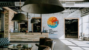 A modern interior with exposed brick walls, a large mural, and a mix of seating arrangements including a glass table and chairs. - SCP WildFree Colorado Springs, Trademark by Wyndham (Colorado Springs)