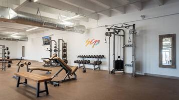 A gym with various exercise equipment, including benches, dumbbells, and weight machines.