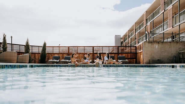 A swimming pool with lounge chairs and a wooden fence. - SCP WildFree Colorado Springs, Trademark by Wyndham (Colorado Springs)