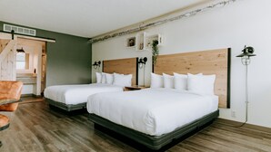 A hotel room with two beds, a wooden headboard, a small table, a chair, and a plant. - SCP WildFree Colorado Springs, Trademark by Wyndham (Colorado Springs)