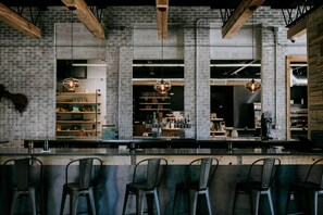 A bar area with a brick wall, wooden beams, and hanging pendant lights. - SCP WildFree Colorado Springs, Trademark by Wyndham (Colorado Springs)