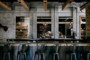 Una zona de bar con pared de ladrillo, vigas de madera y lámparas colgantes.