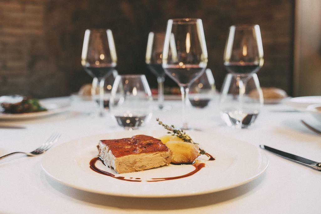 Una mesa de comedor con un plato de comida y varias copas de vino.