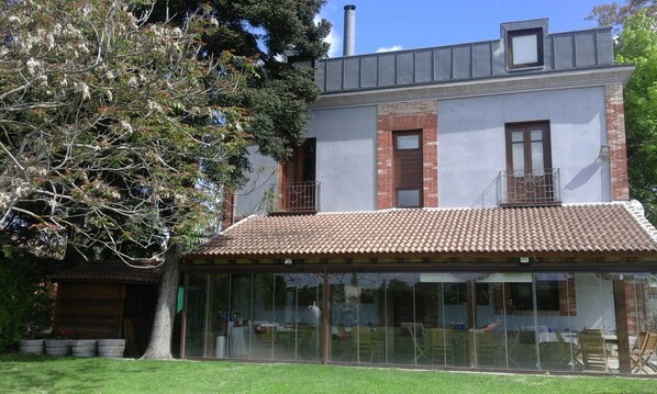 A two-story building with a tiled roof, large windows, and a balcony.