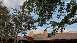 Ein rustikaler Außenbereich mit Adirondack-Stühlen, einem Steinhaus und einer überdachten Terrasse.