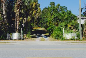 A road leading through a lush, green area with white picket fences on both sides.
