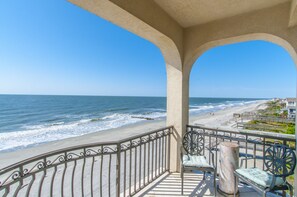 A balcony with a view of the beach and ocean.