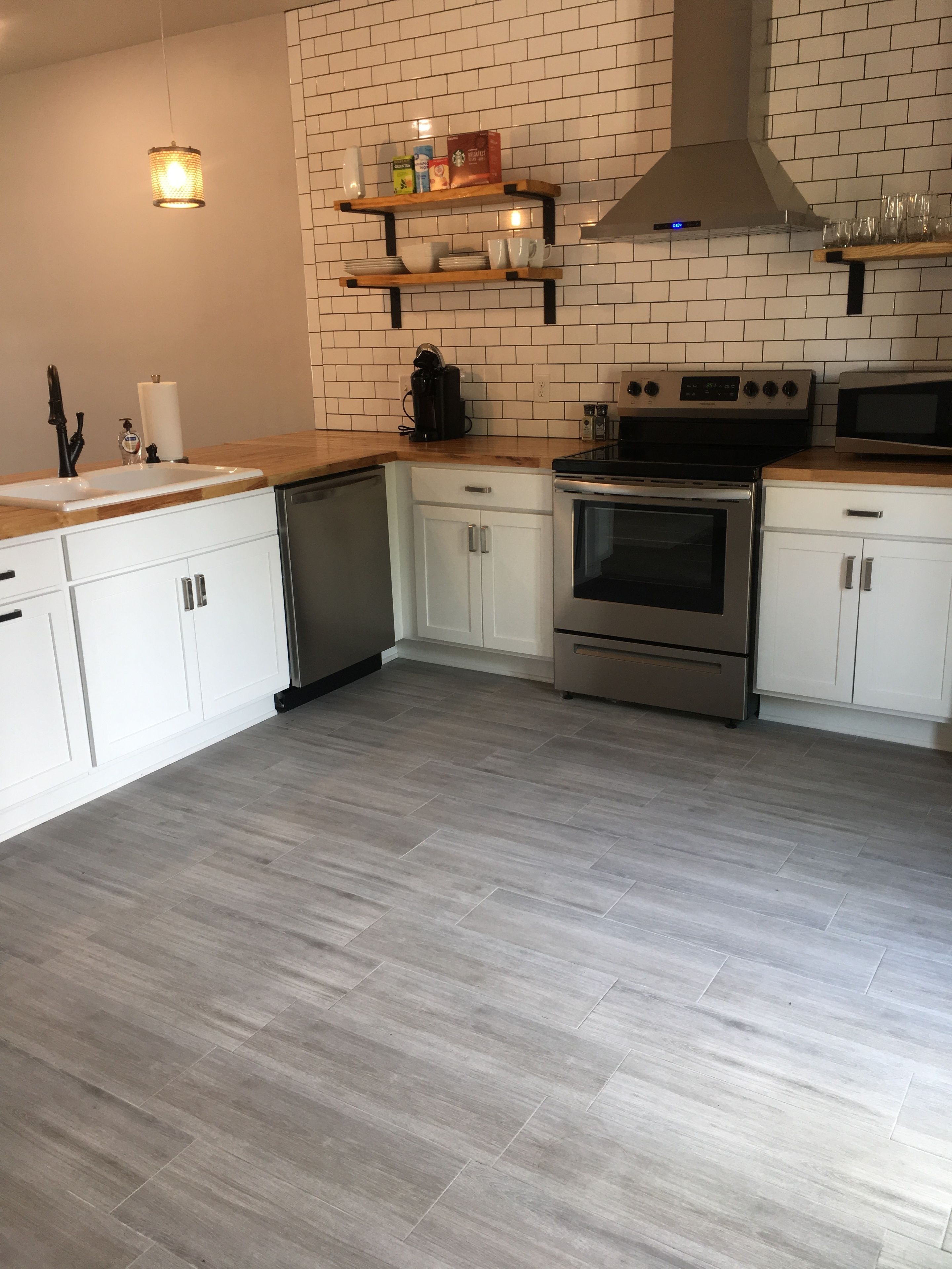 Una cocina moderna con armarios blancos, horno de acero inoxidable, microondas y cafetera sobre la encimera.