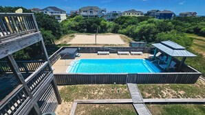 A backyard with a swimming pool, a wooden deck, and a covered seating area. - 3rd row Whalehead house w/ private pool, hot tub, elevator, pool table, pet friendly (Corolla)