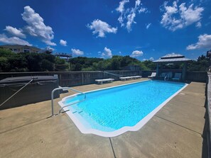 Ein rechteckiger Swimmingpool mit weißem Rand, umgeben von einer Betonplattform.