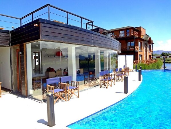 Una piscina al aire libre, sillones reclinables de piscina