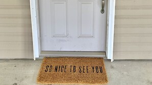 A white door with a brass knocker, a doormat with text, and a keyhole. - Spacious, budget friendly 3 BR House! (Gulf Shores)