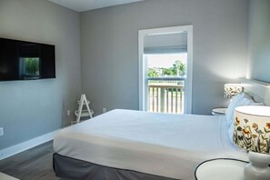 Ein Schlafzimmer mit einem Bett, einem an der Wand montierten Fernseher, einem Fenster mit Blick ins Freie und einer Leiter.