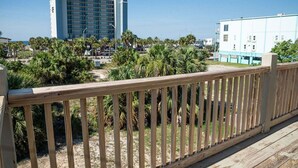 Un hotel sulla spiaggia con un pontile in legno, palme e vista libera sull'oceano.