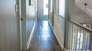 Un corridoio con pavimento in legno, ringhiere bianche e luci a soffitto.
