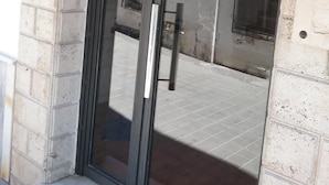 A hotel entrance with a glass door, a blue sign indicating a hotel, and a visible fire alarm. - Hostal Cabrera (Motril)