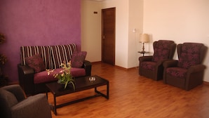 A living room with a sofa, two armchairs, a coffee table, and a lamp. - Hostal Cabrera (Motril)