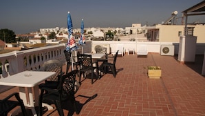 A rooftop terrace with outdoor seating, a view of the city, and a brick floor. - Hostal Cabrera (Motril)