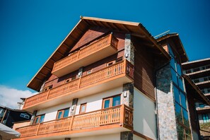 A multi-story building with wooden balconies and large windows. - Chalet Valluga (Lo Barnechea)