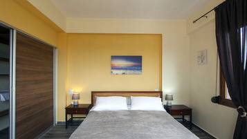 A hotel room with a bed, two bedside tables with lamps, a painting on the wall, and a window with curtains.