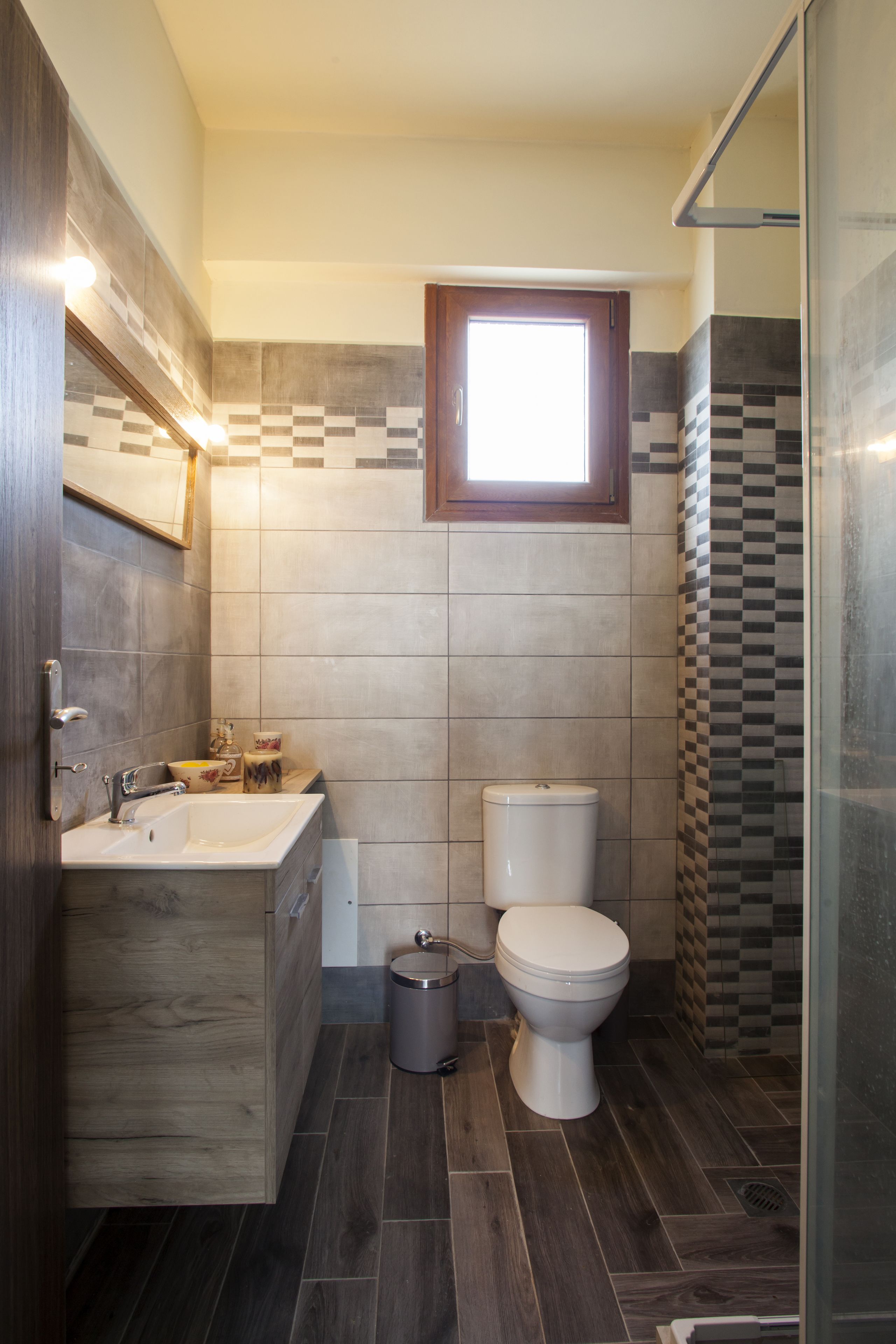 Une salle de bain moderne avec un meuble-lavabo en bois, un évier, des toilettes et un espace douche.
