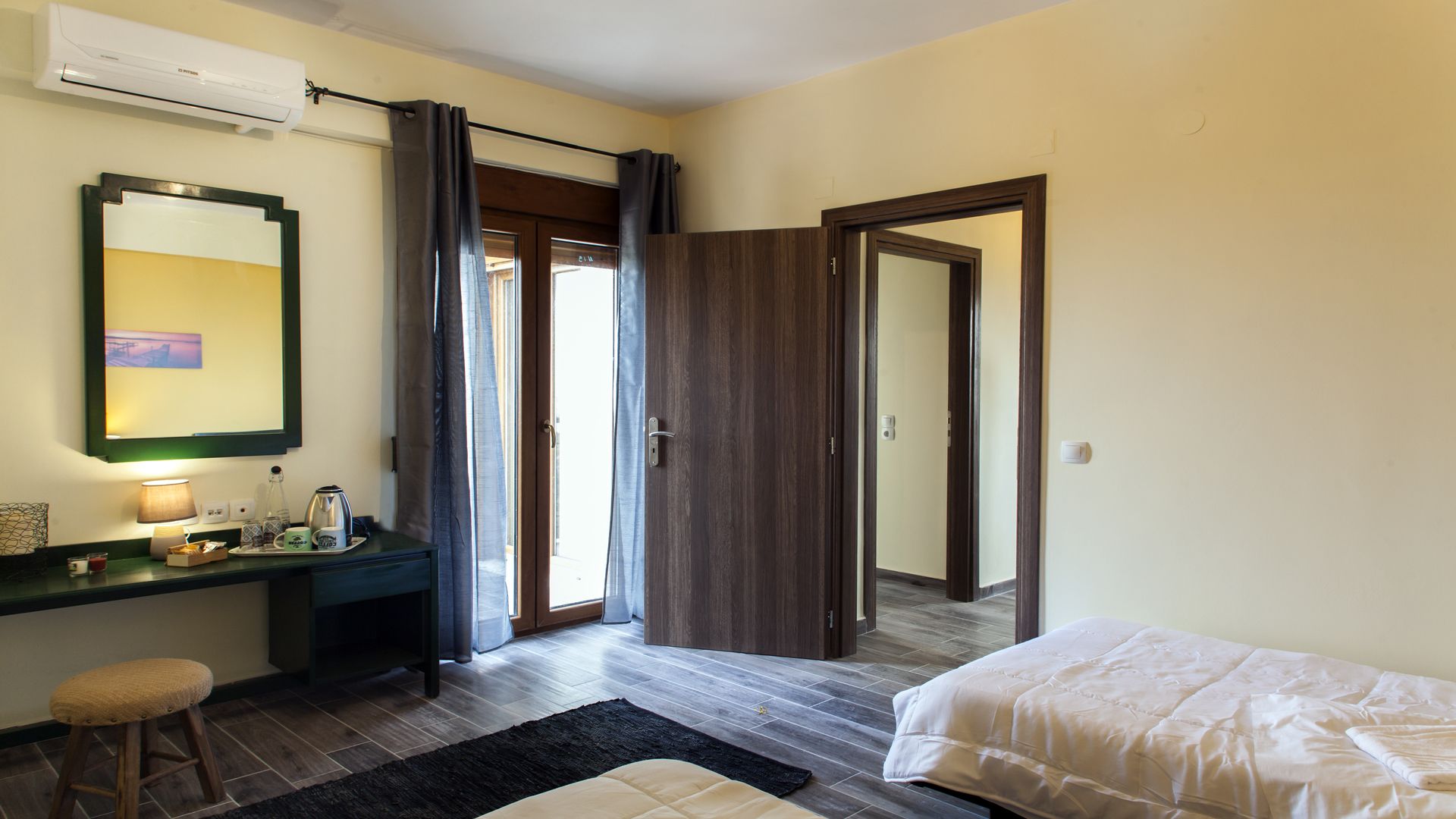 Una habitación de hotel con cama, escritorio con lámpara, espejo y armario.