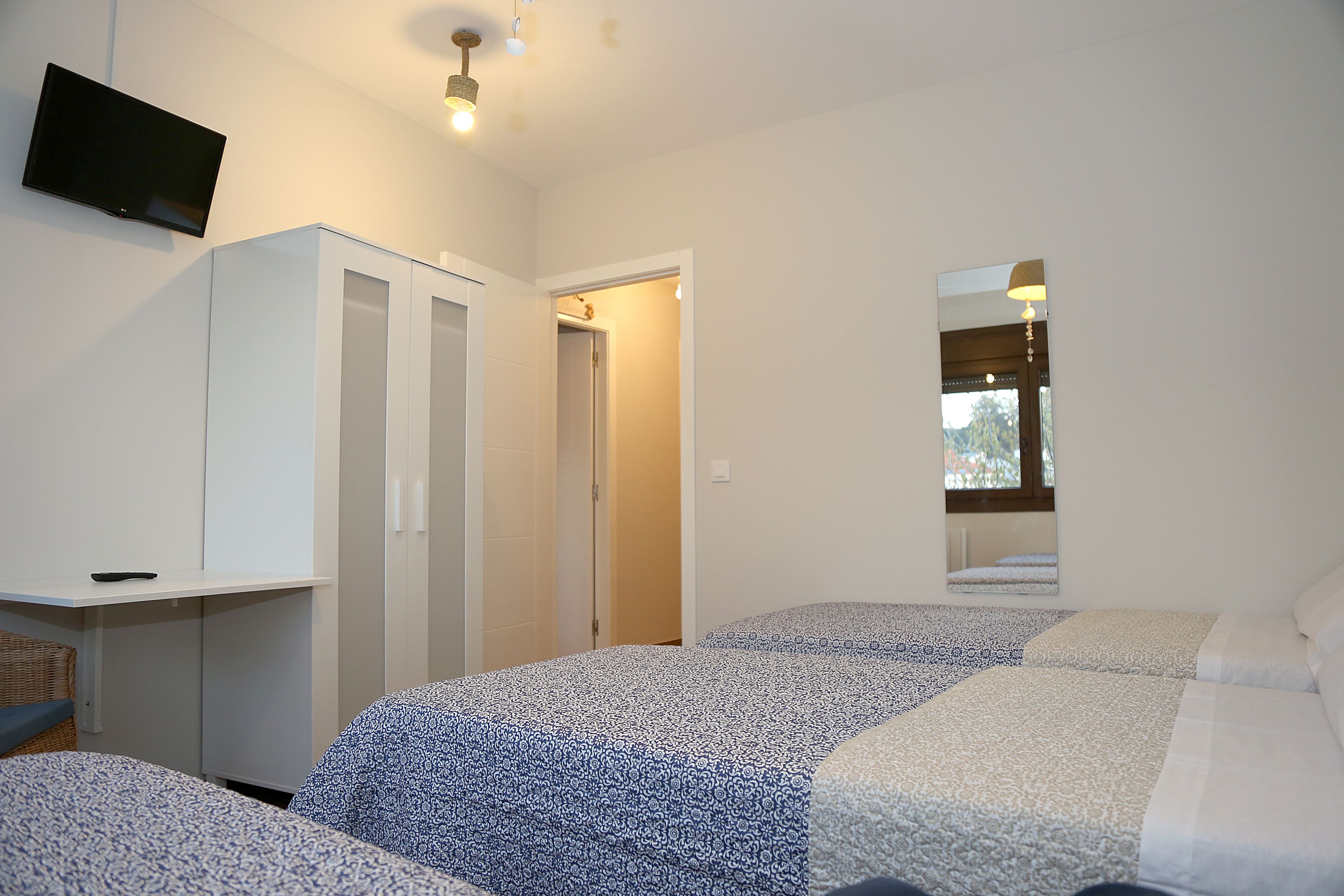 Ein Schlafzimmer mit zwei Betten, einem Fernseher, einem Kleiderschrank und einem Spiegel.