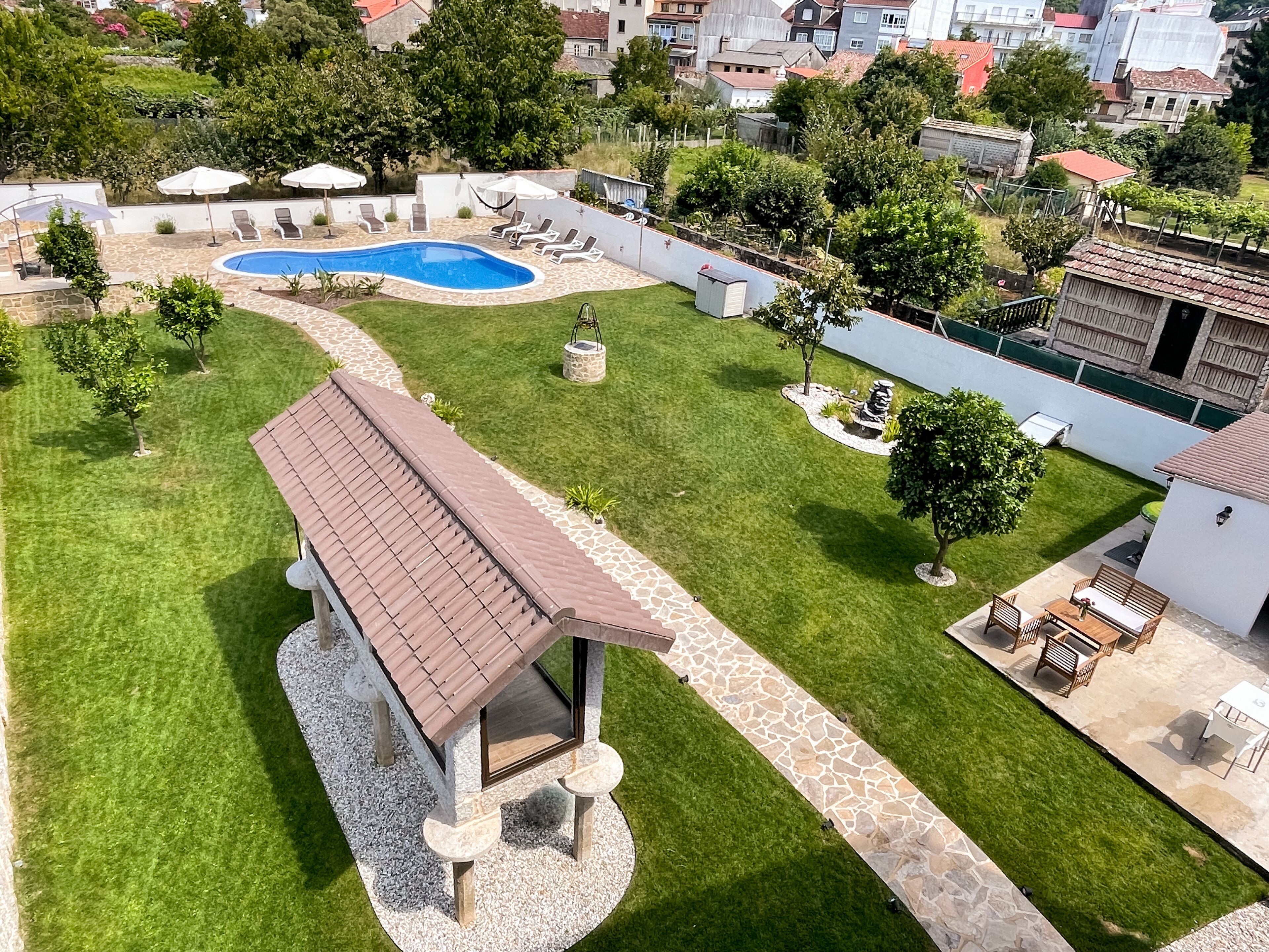 A well-maintained backyard with a swimming pool, a covered seating area, and a stone pathway.