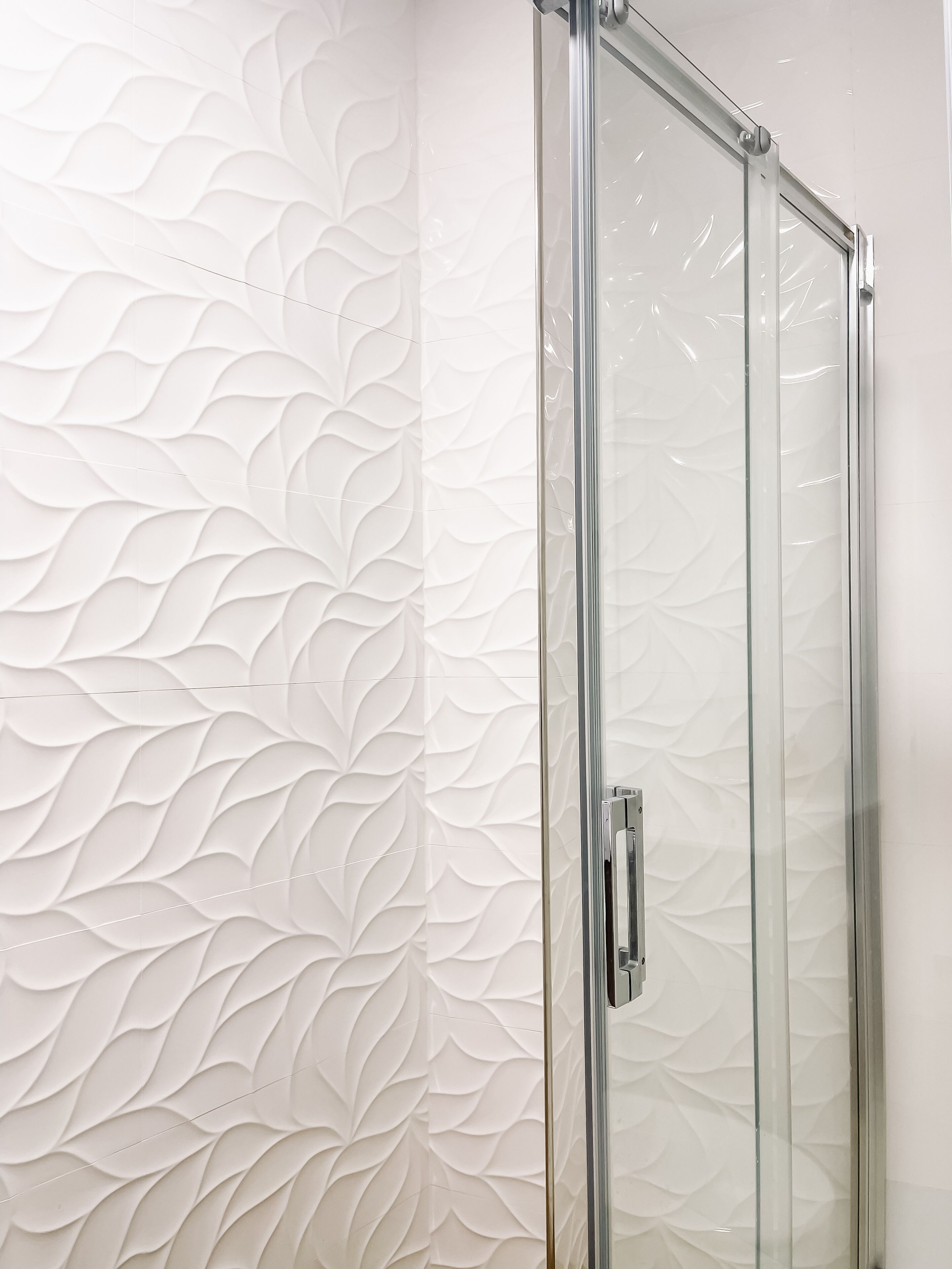 A modern bathroom with a textured wall and a glass shower enclosure.