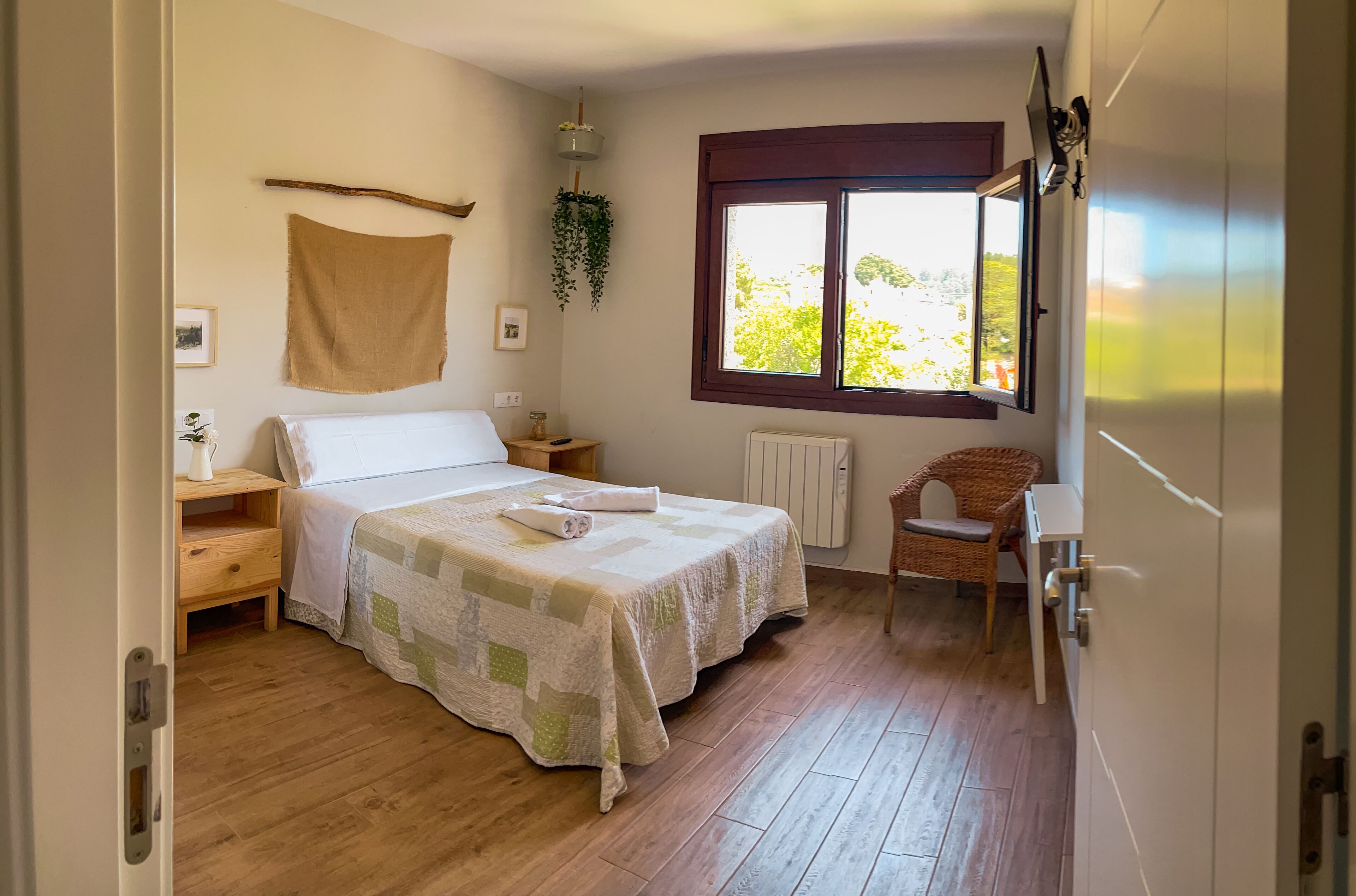 Un dormitorio con cama, ventana, una silla, un radiador y suelo de madera.