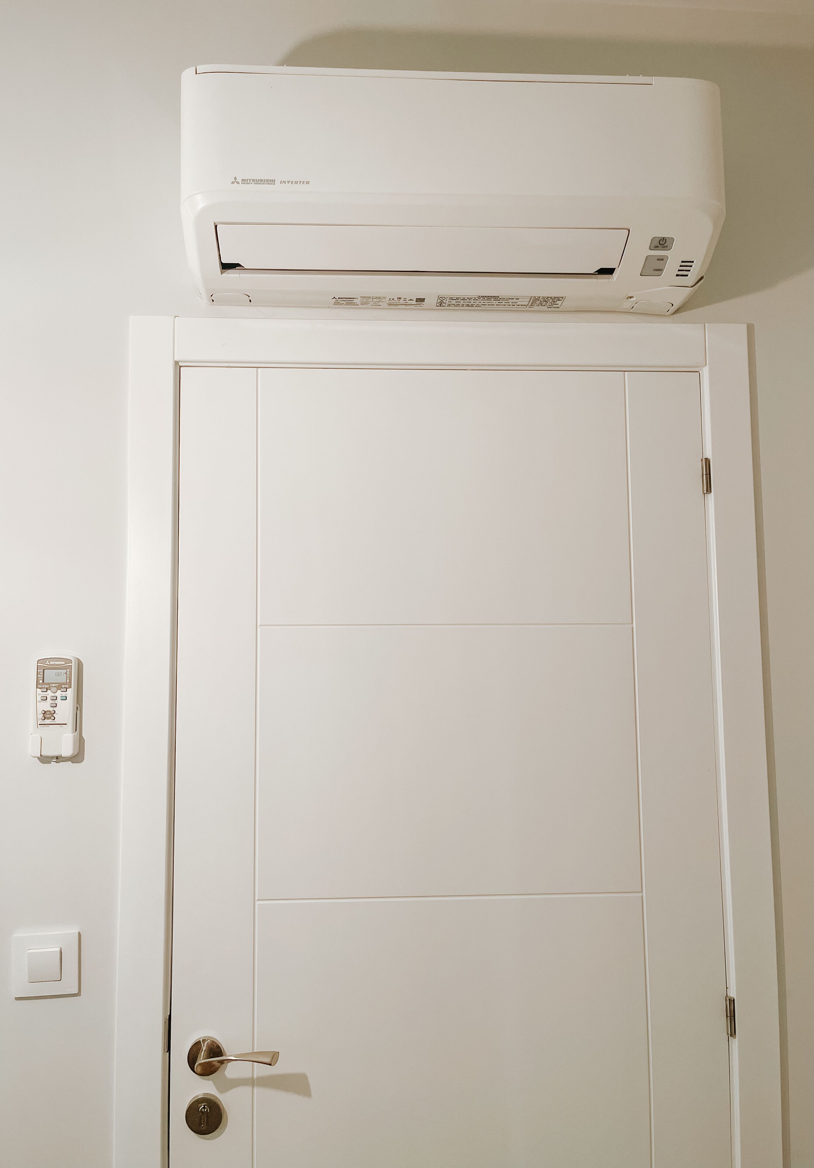 Una puerta blanca con un aire acondicionado de pared.