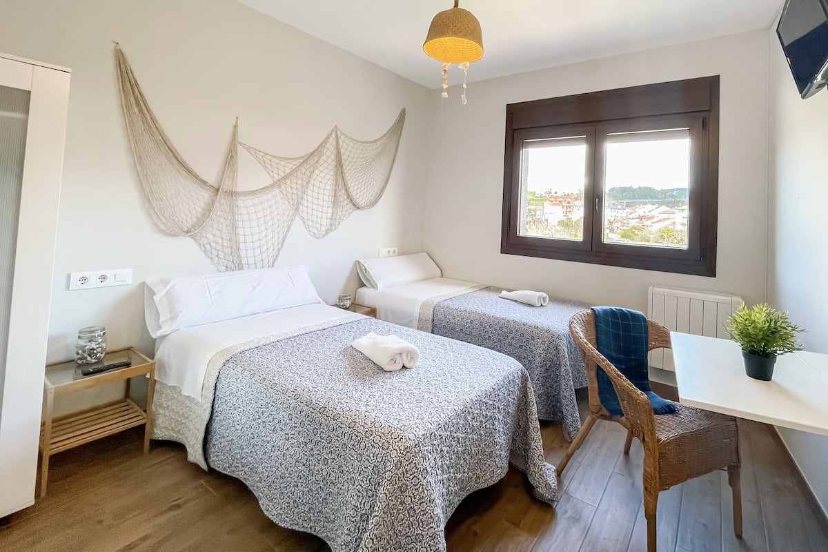 Une chambre avec deux lits, un bureau et une fenêtre.