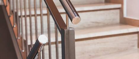 Una escalera con barandilla de metal y pared de madera.