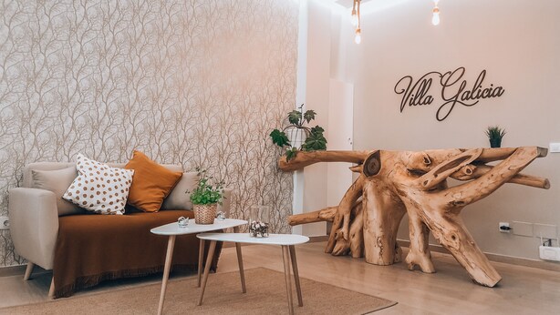 A modern living room with a sofa, coffee table, and a unique wooden sculpture.